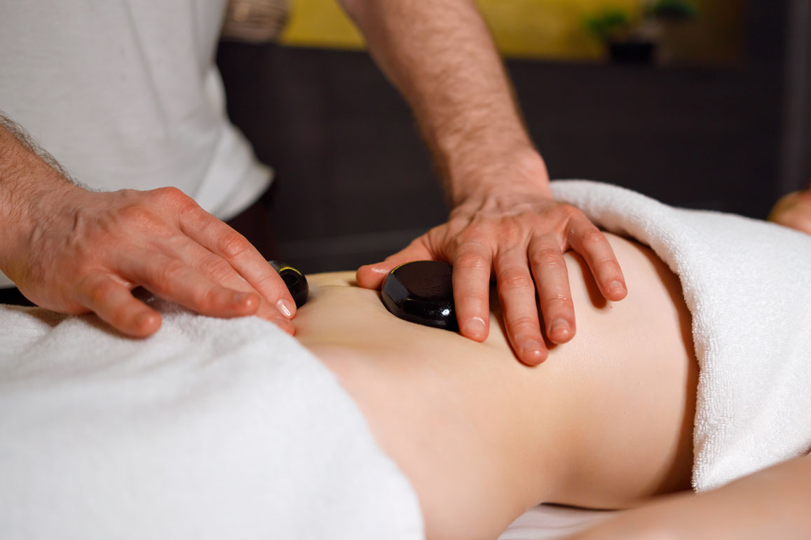 masseur-massaging-woman-s-abdomen-with-lava-stones-2024-10-22-03-57-00-utc